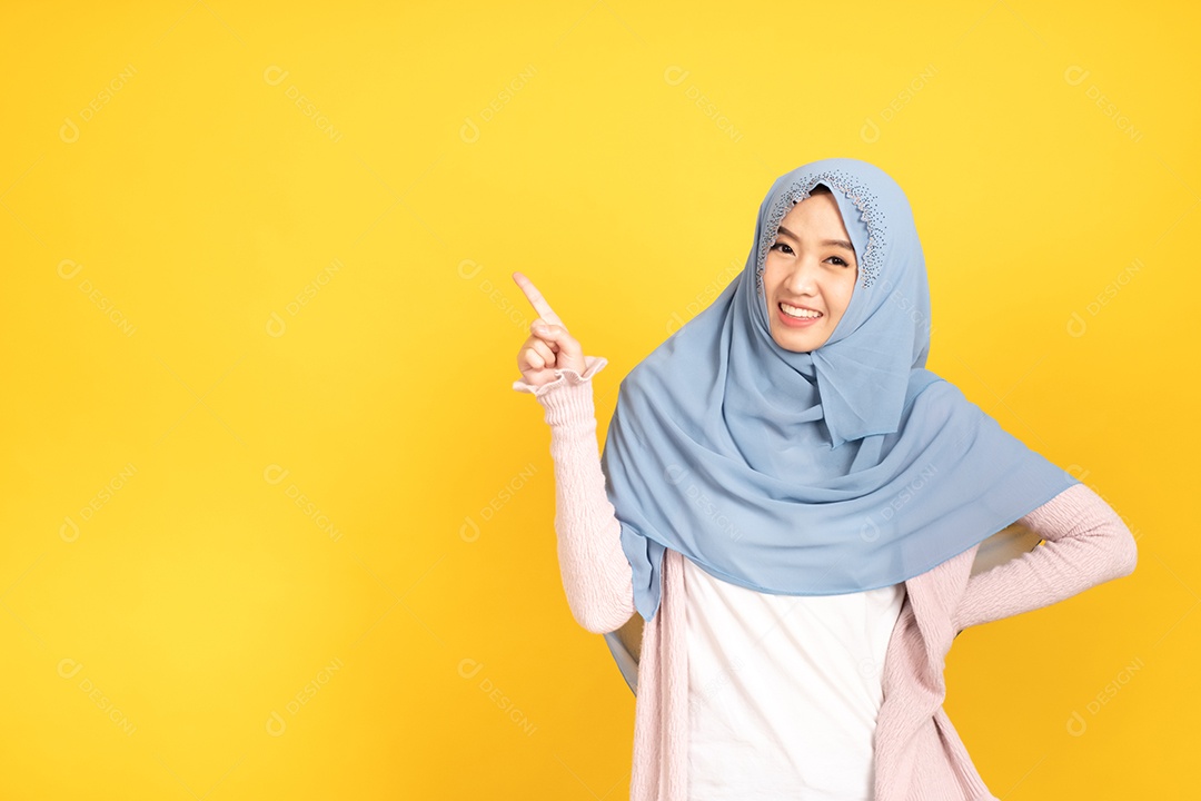 Retrato de menina muçulmana asiática em hijab apontando as mãos de lado.