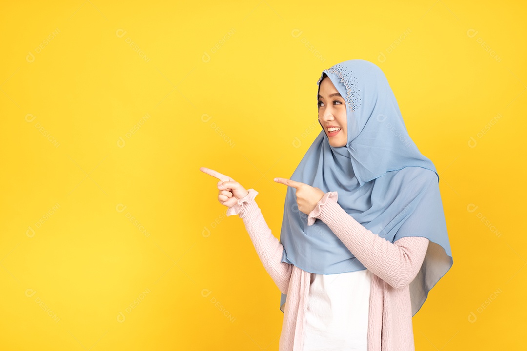 Retrato de menina muçulmana asiática em hijab apontando as mãos de lado.