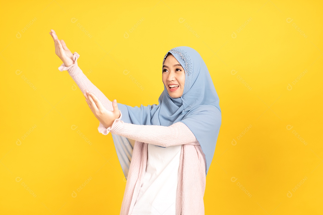 Retrato de menina muçulmana asiática em hijab apontando as mãos de lado.
