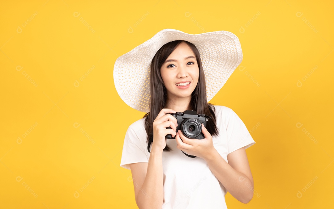 Feliz sorridente jovem fotógrafa asiática usando chapéu e segurando câmera