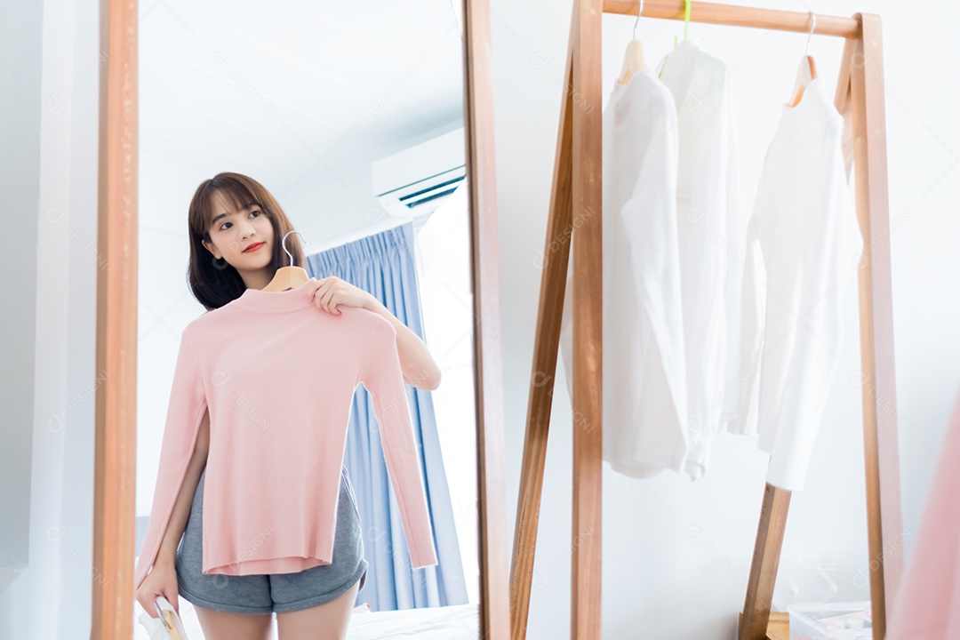 Mulher asiática escolhendo roupas olhando no espelho