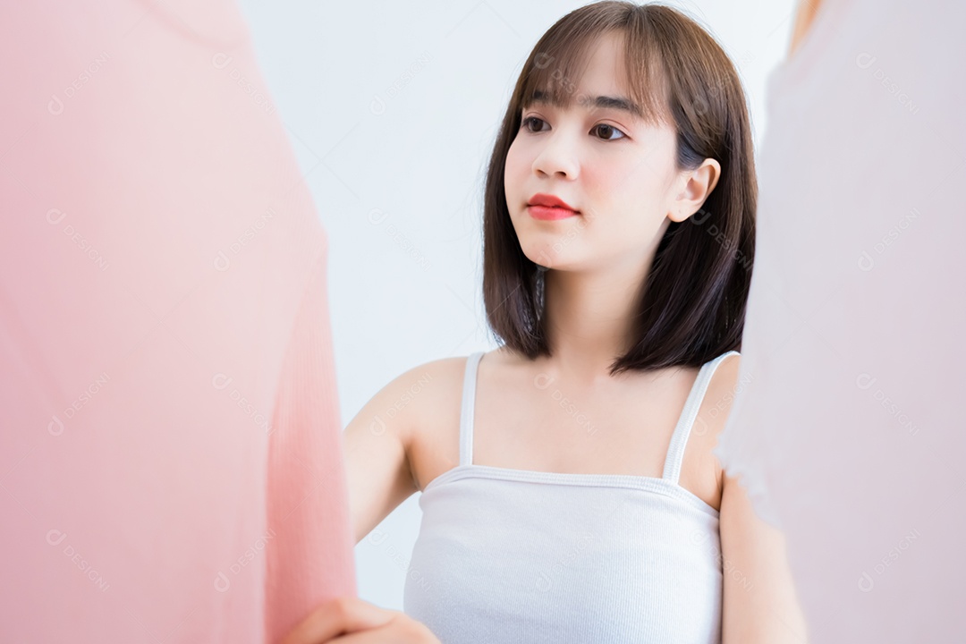 Mulher asiática escolhendo roupas olhando no espelho