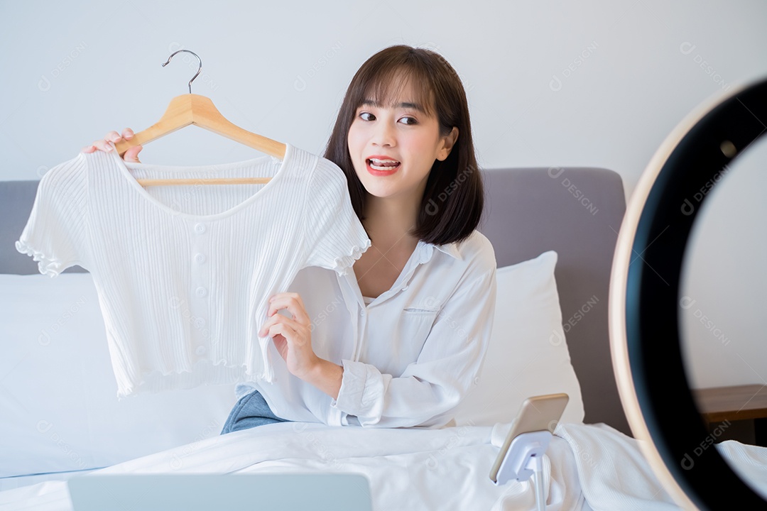 Linda mulher asiática vlogger gravando roupas penduradas