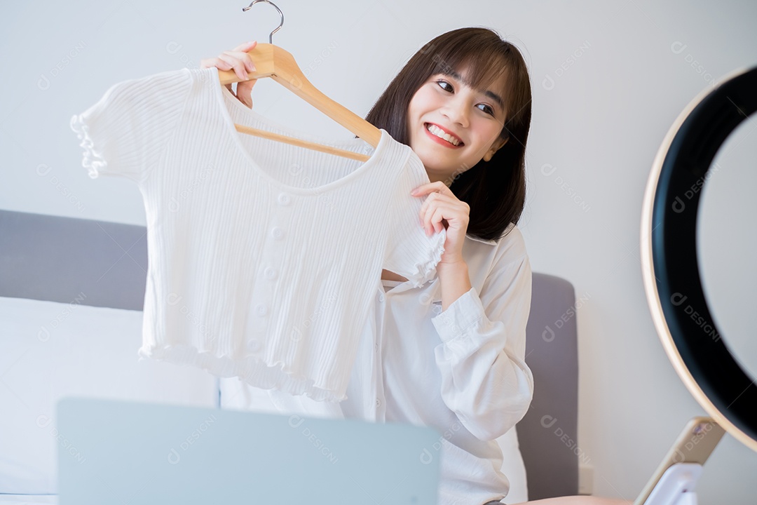 Linda mulher asiática vlogger gravando roupas penduradas