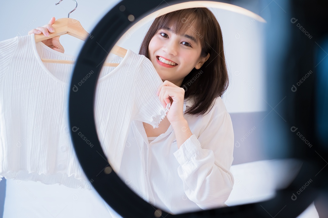 Linda mulher asiática vlogger gravando roupas penduradas