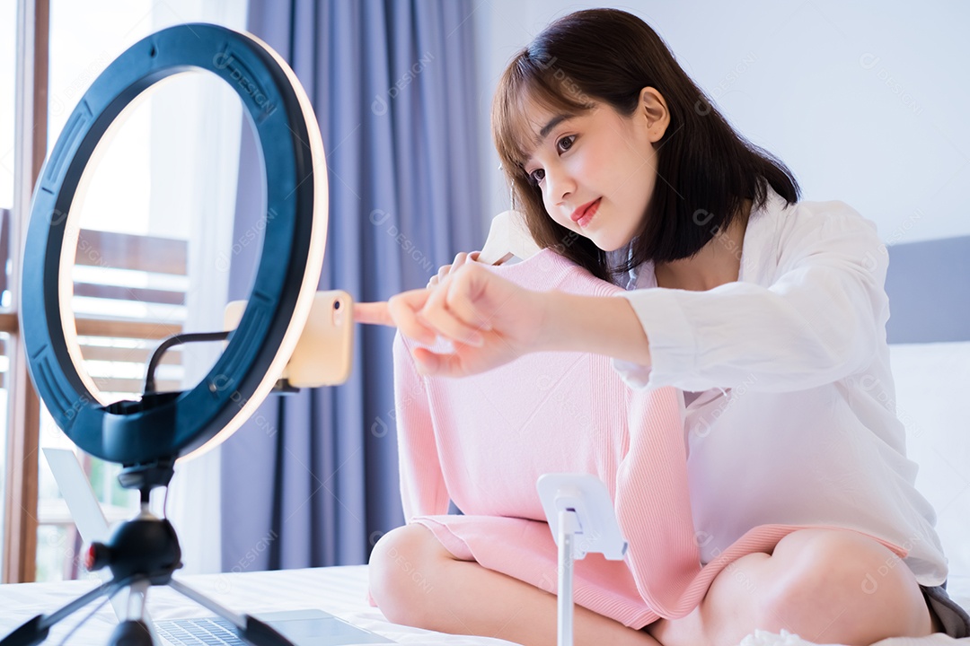 Linda mulher asiática vlogger gravando roupas penduradas