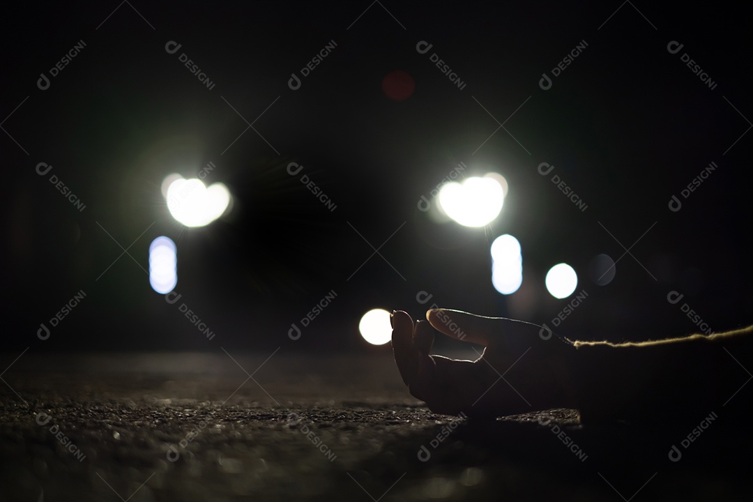 Mão mulher caída no chão e farol do carro