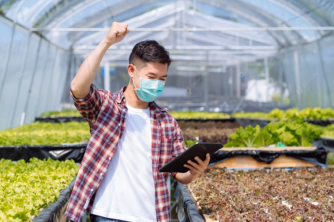 Jovem asiático agricultor trabalhando no fundo da fazenda hidropônica