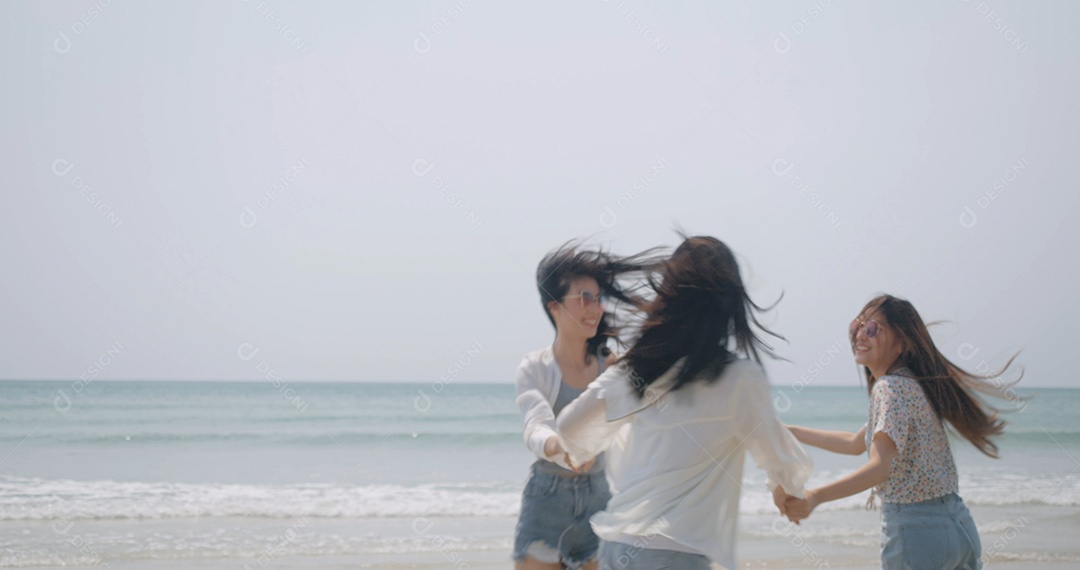 Sorrindo, amigos asiáticos felizes, mulheres correndo e pulando juntos à beira-mar na praia