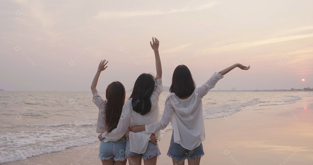 Sorrindo, amigos asiáticos felizes, mulheres correndo e pulando juntos à beira-mar na praia