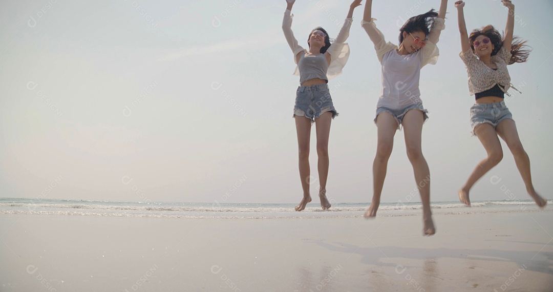 Sorrindo, amigos asiáticos felizes, mulheres correndo e pulando juntos à beira-mar na praia