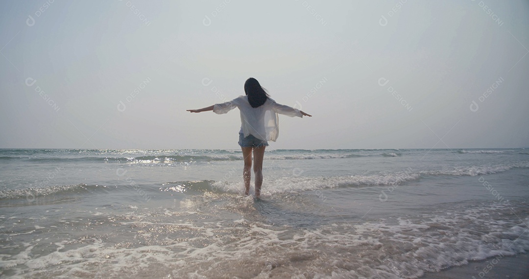 Jovem mulher asiática correndo aproveitando a vida na praia