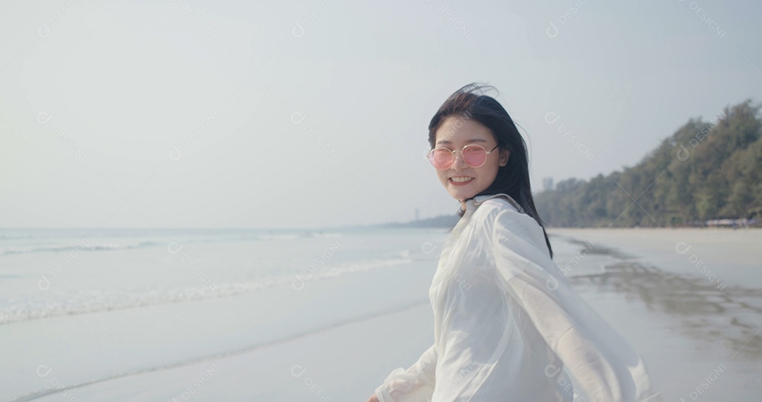 Linda jovem asiática caminhando aproveitando a vida na praia