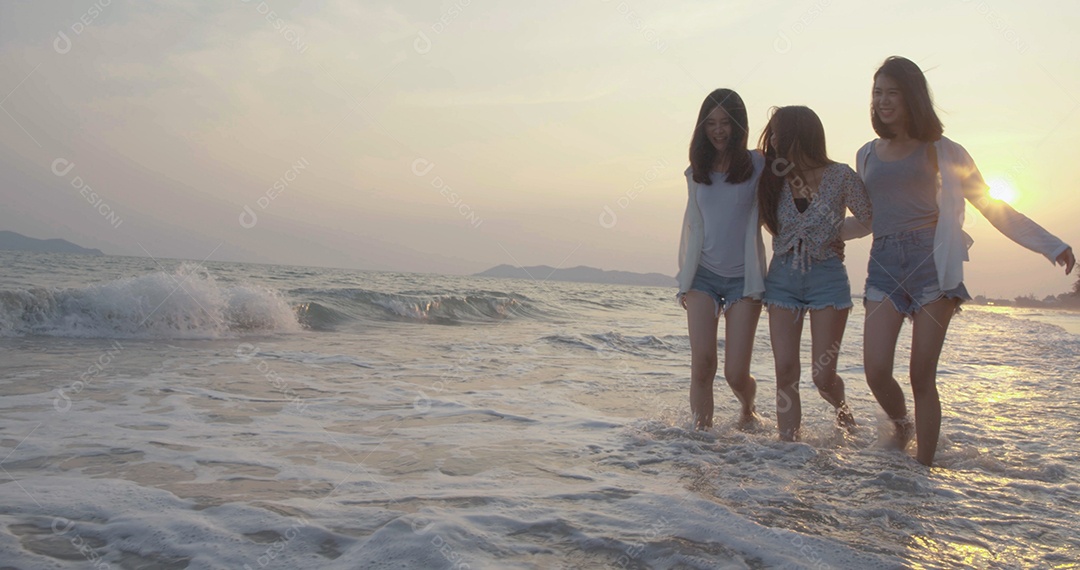 Amigas asiáticas mulheres correndo e pulando juntas à beira-mar