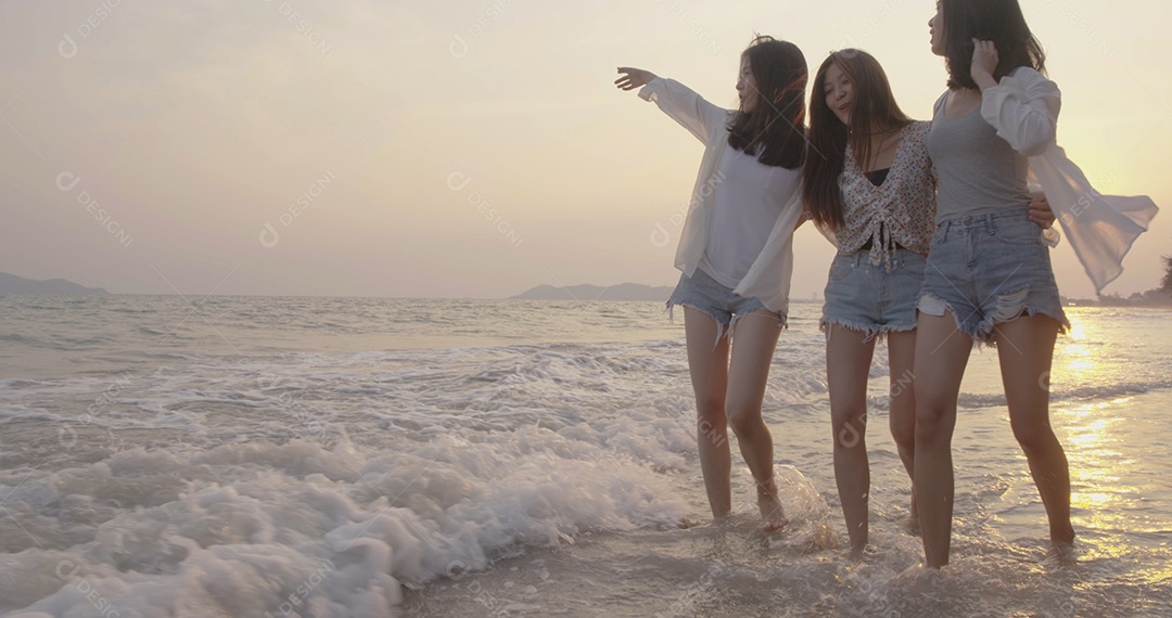 Amigas asiáticas mulheres correndo e pulando juntas à beira-mar