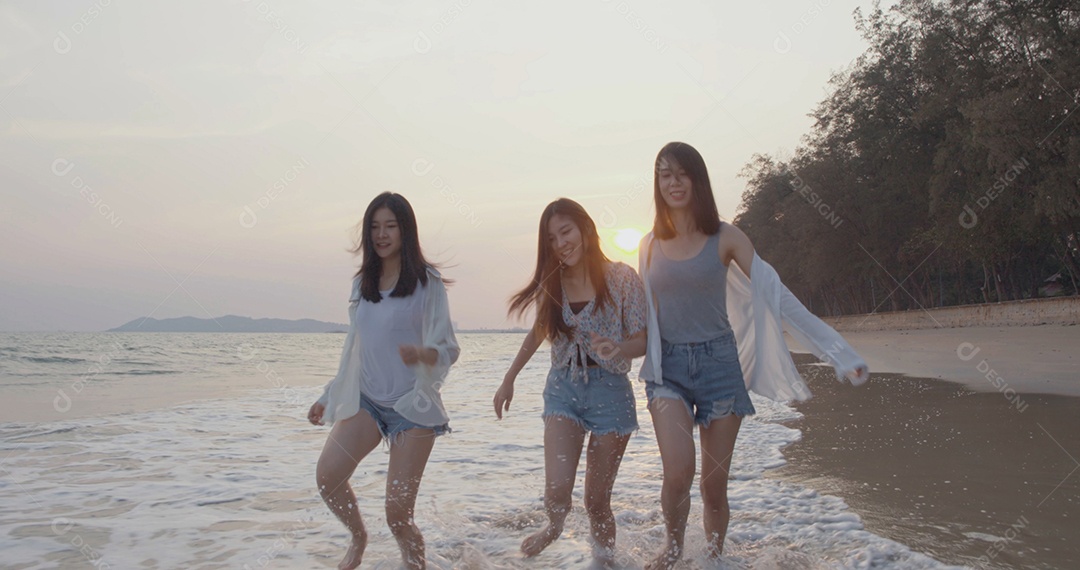 Amigas asiáticas mulheres correndo e pulando juntas à beira-mar