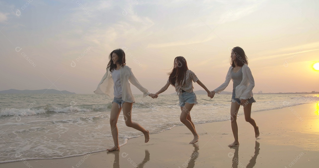 Amigos asiáticos felizes, mulheres correndo juntas à beira-mar na praia