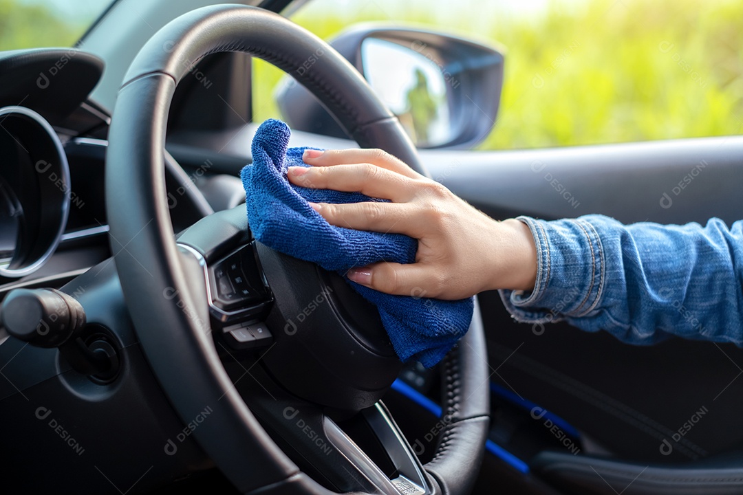 Mulher com pano de microfibra limpando carro com álcool