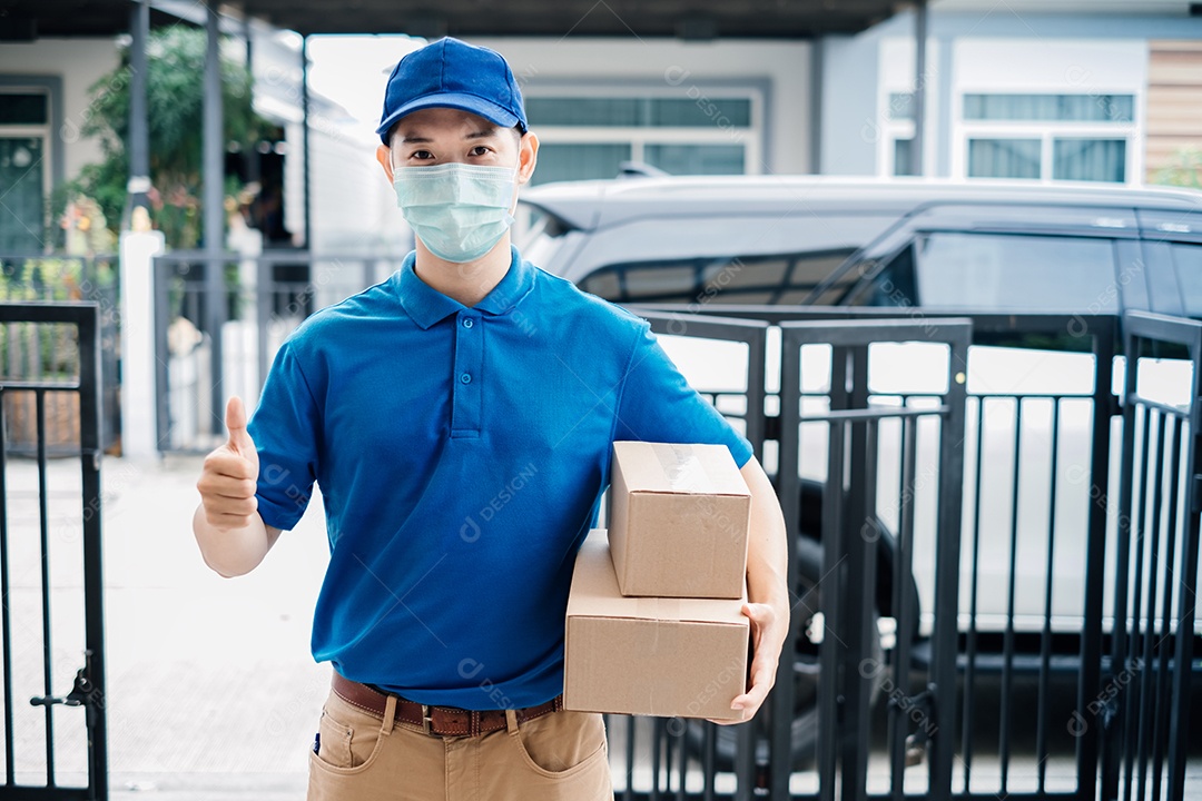O entregador asiático usando máscara pegando o pacote no transporte para entregas