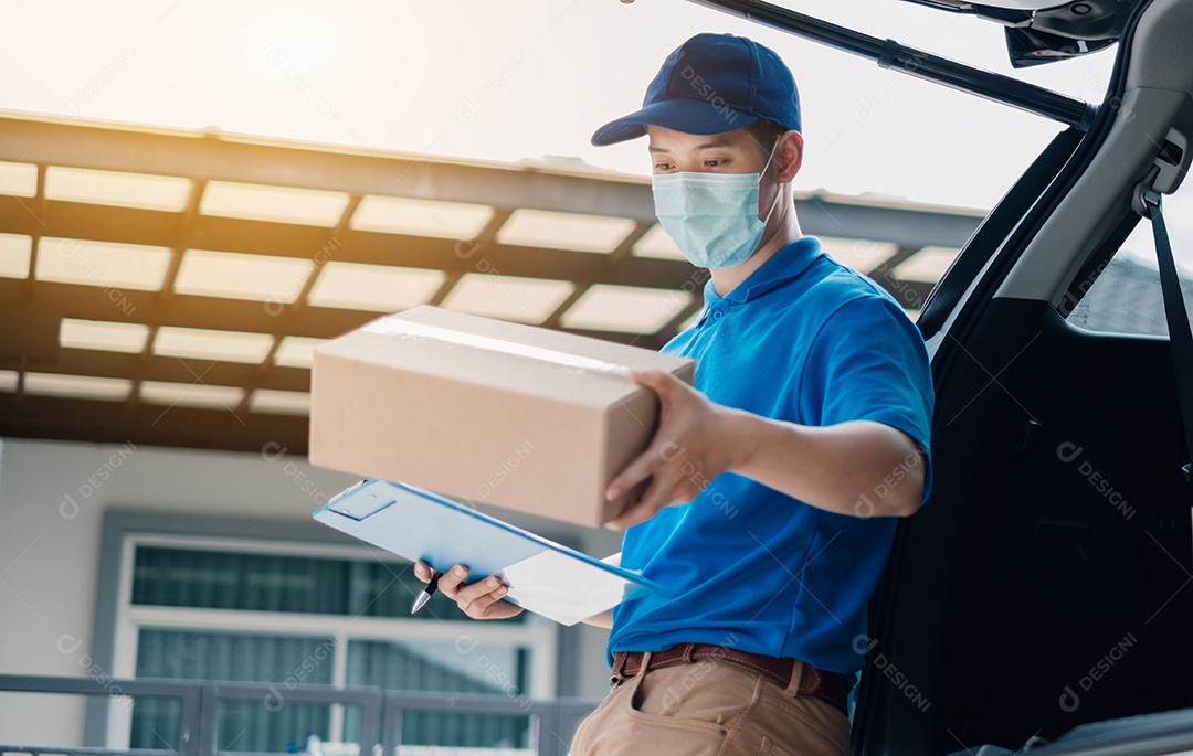 O entregador asiático usando máscara pegando o pacote no transporte para entregas