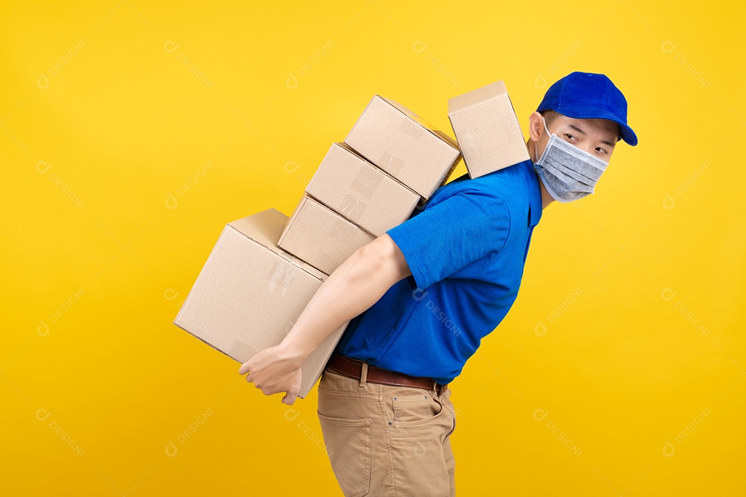 Homem bonito de entrega usando máscara com muitas caixas de papelão pesadas