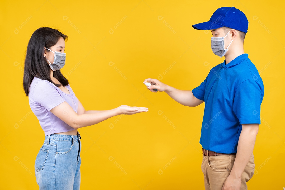 O entregador asiático usando máscara envia um pacote aplicando spray de limpeza na mão da cliente