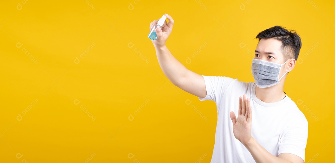 Homem asiático bonito usando máscara mostrando spray de álcool desinfetante para as mãos