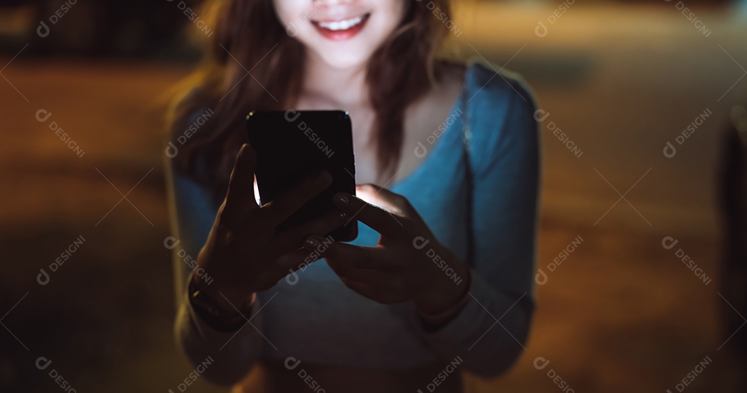 Mulher de beleza olhando smartphone celular à noite na rua