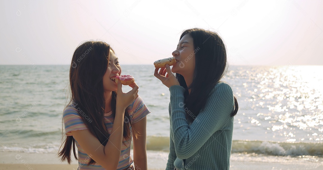 Meninas sorridentes com donuts na praia