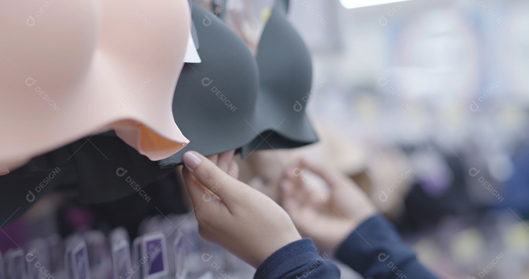 Uma jovem de compras escolhe sutiã de roupas íntimas em uma loja de shopping