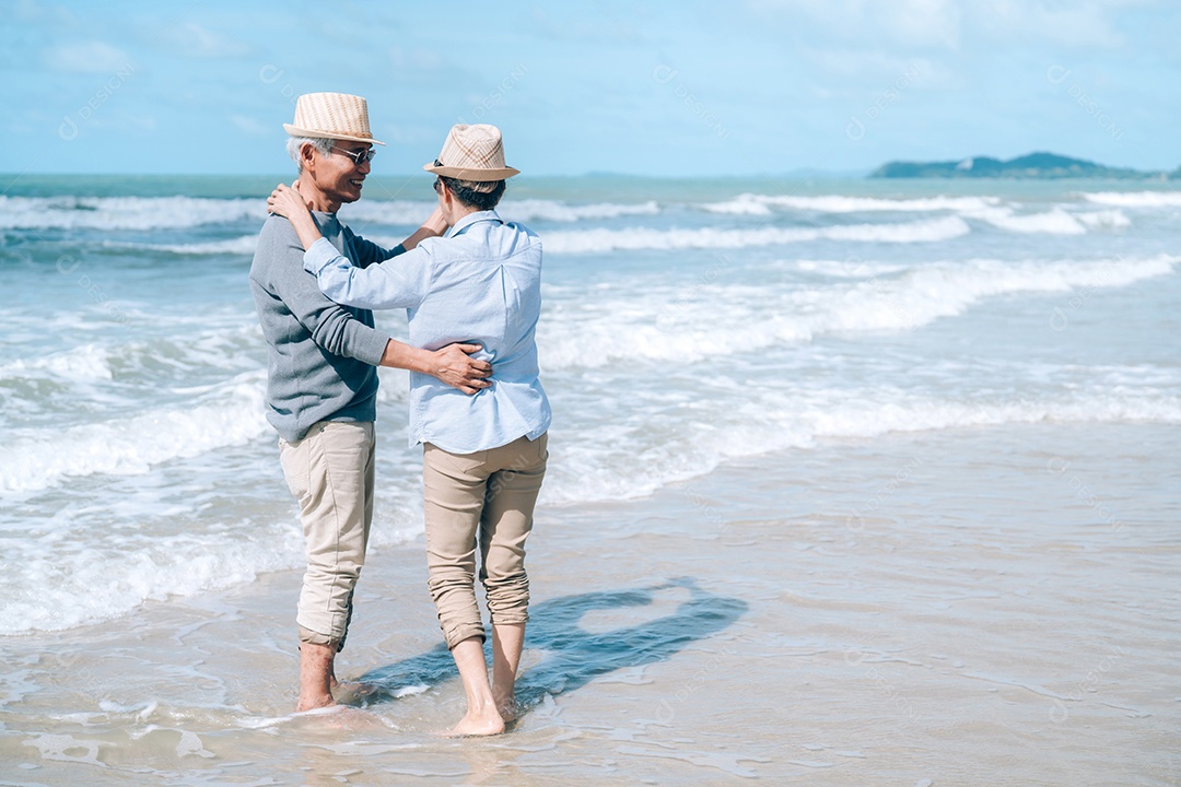 Feliz casal asiático de idosos descansando na praia