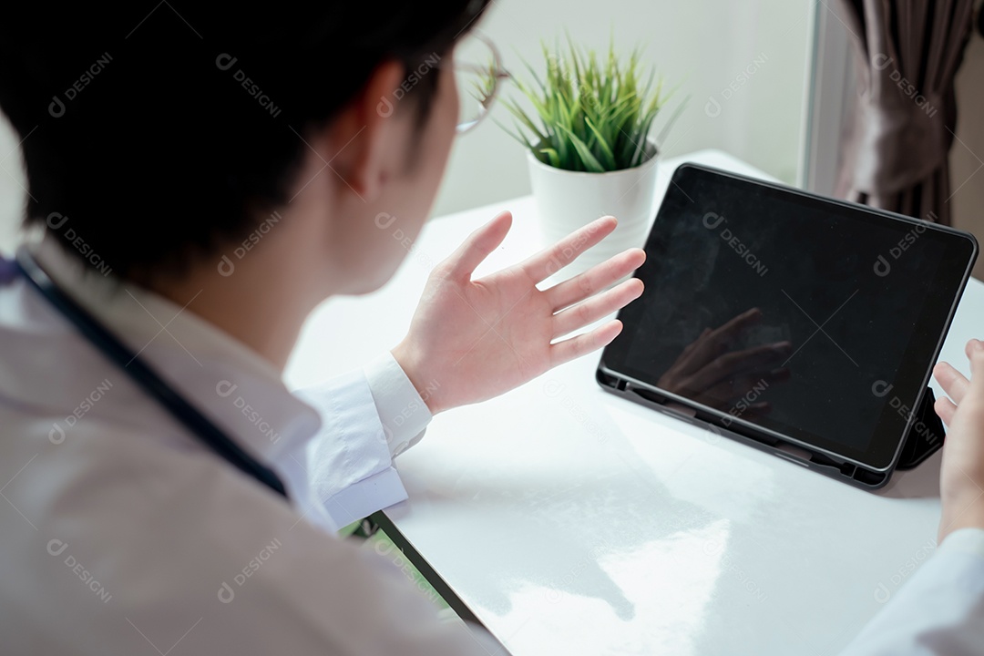 Jovem médico asiático em consultório usando tablet digital