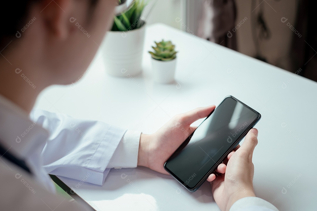 Jovem médico asiático em consultório usando smartphone