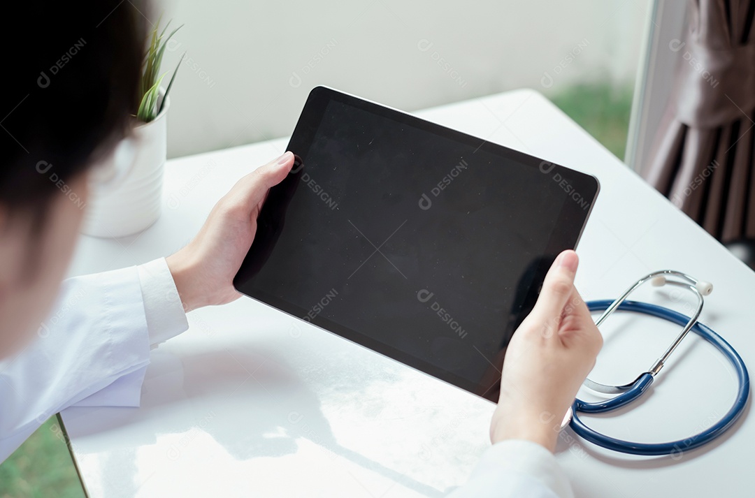 Jovem médico asiático em consultório usando tablet digital