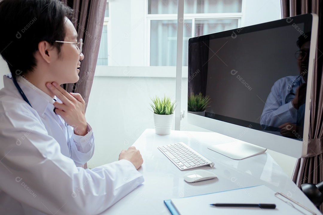 Jovem médico asiático em consultório usando computador portátil