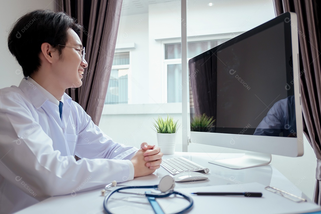 Jovem médico asiático em consultório usando computador portátil