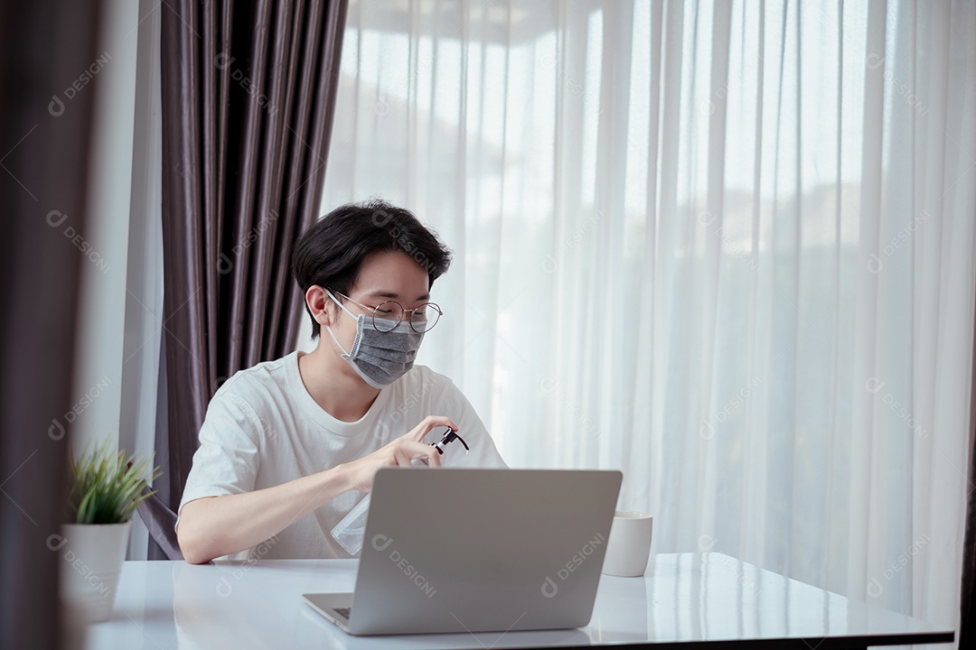 Homem asiático usando máscara trabalhando em casa com computador