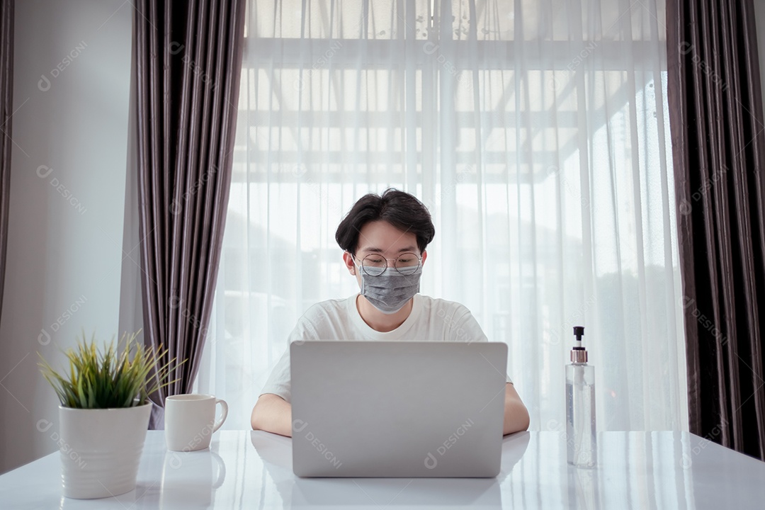 Homem asiático usando máscara trabalhando em casa com computador