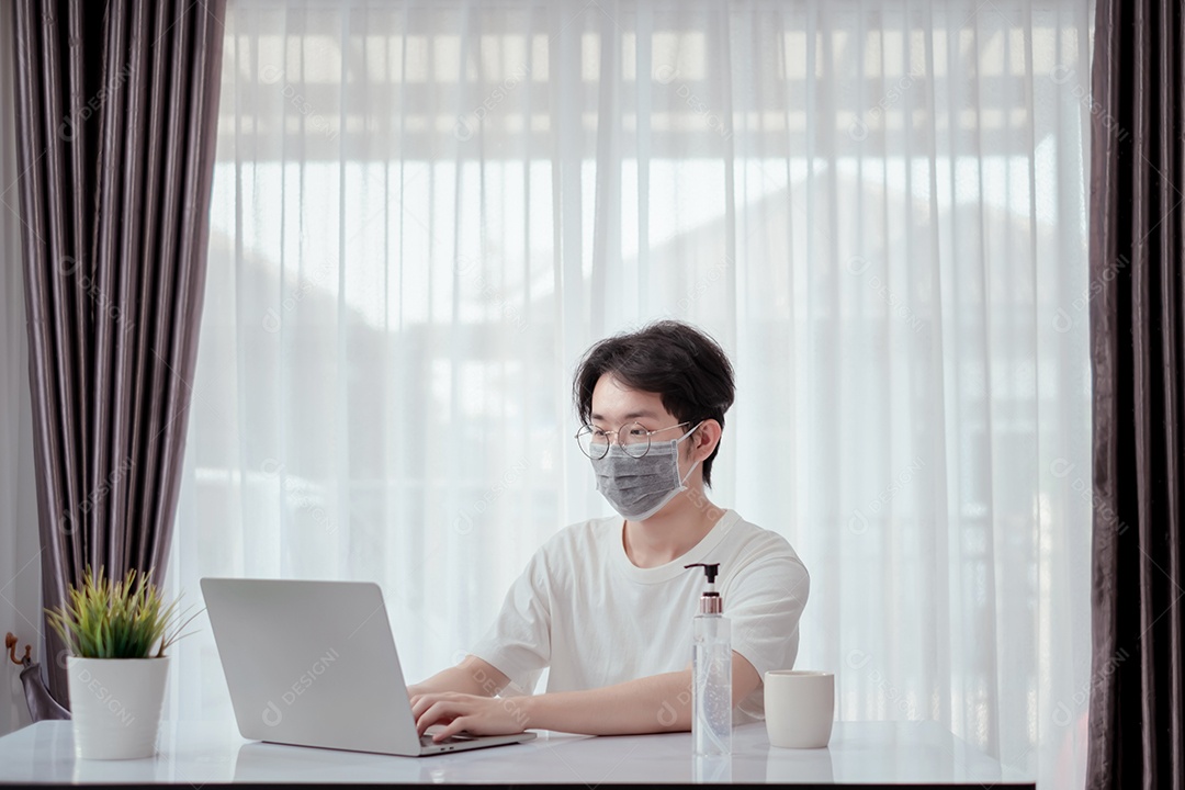 Homem asiático usando máscara trabalhando em casa com computador