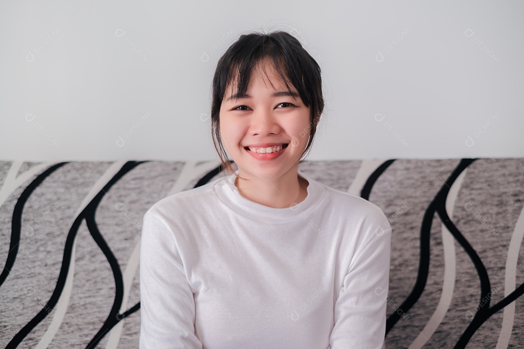 Mulher asiática sorridente sentada no sofá