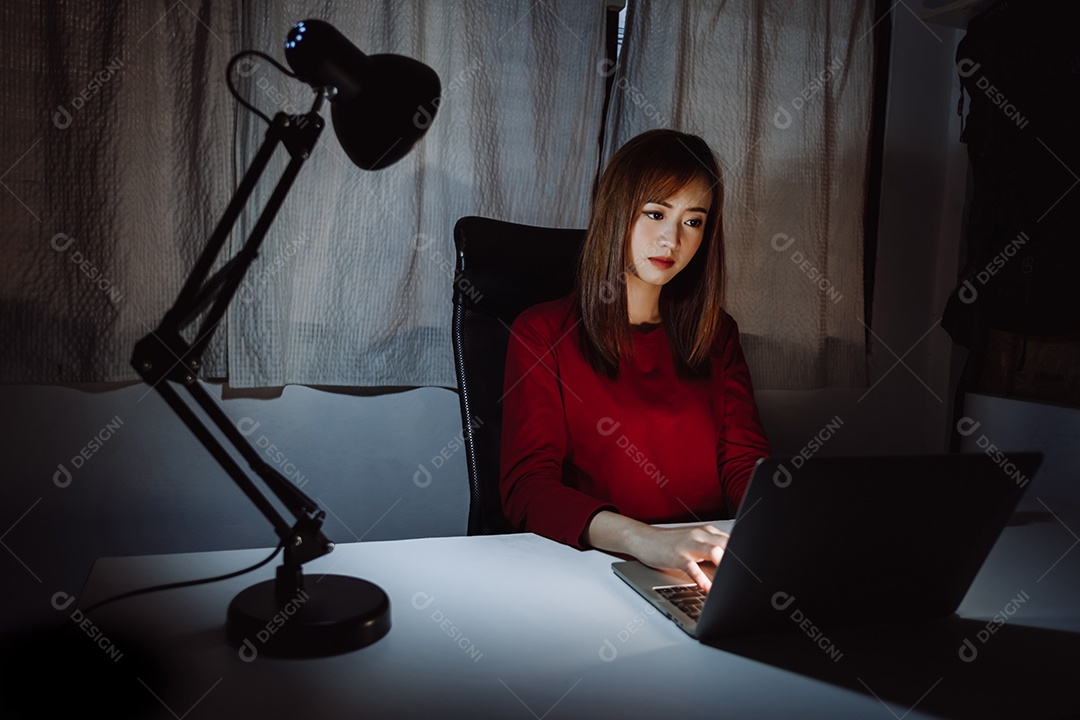 Mulher asiática trabalhando tarde da noite com laptop em casa