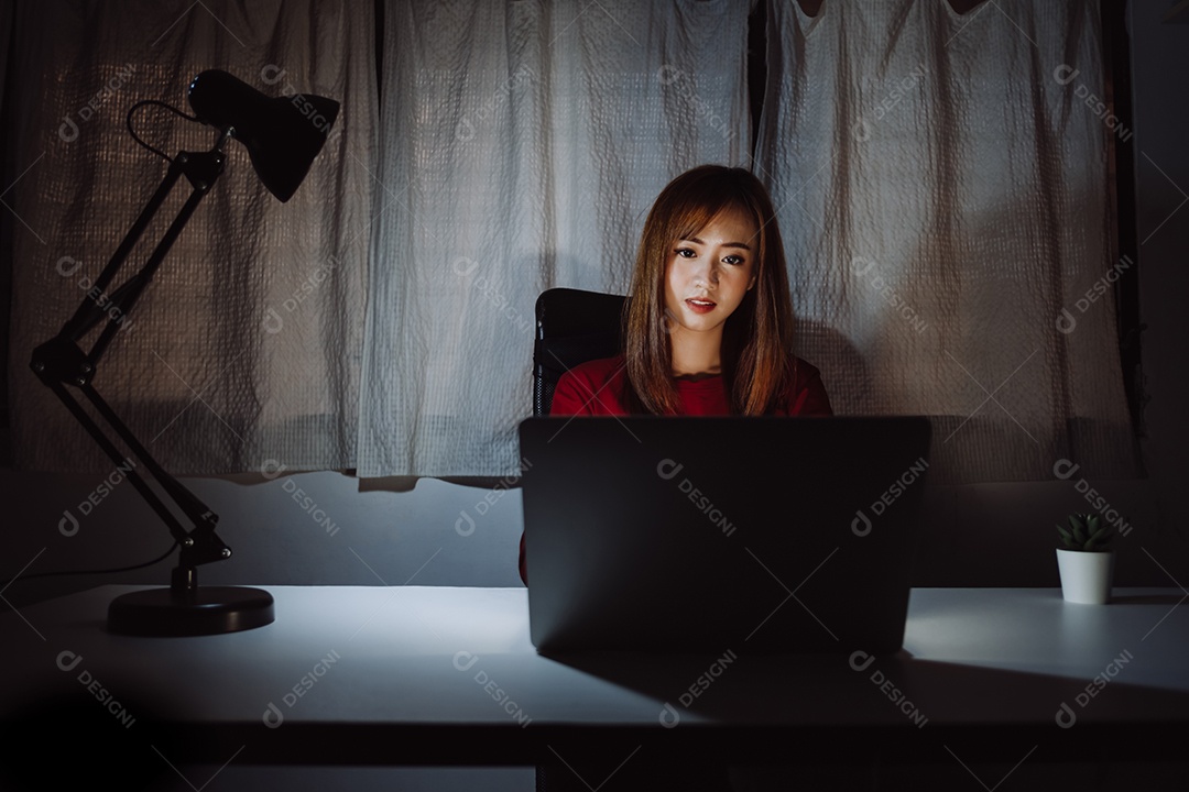 Mulher asiática trabalhando tarde da noite com laptop em casa