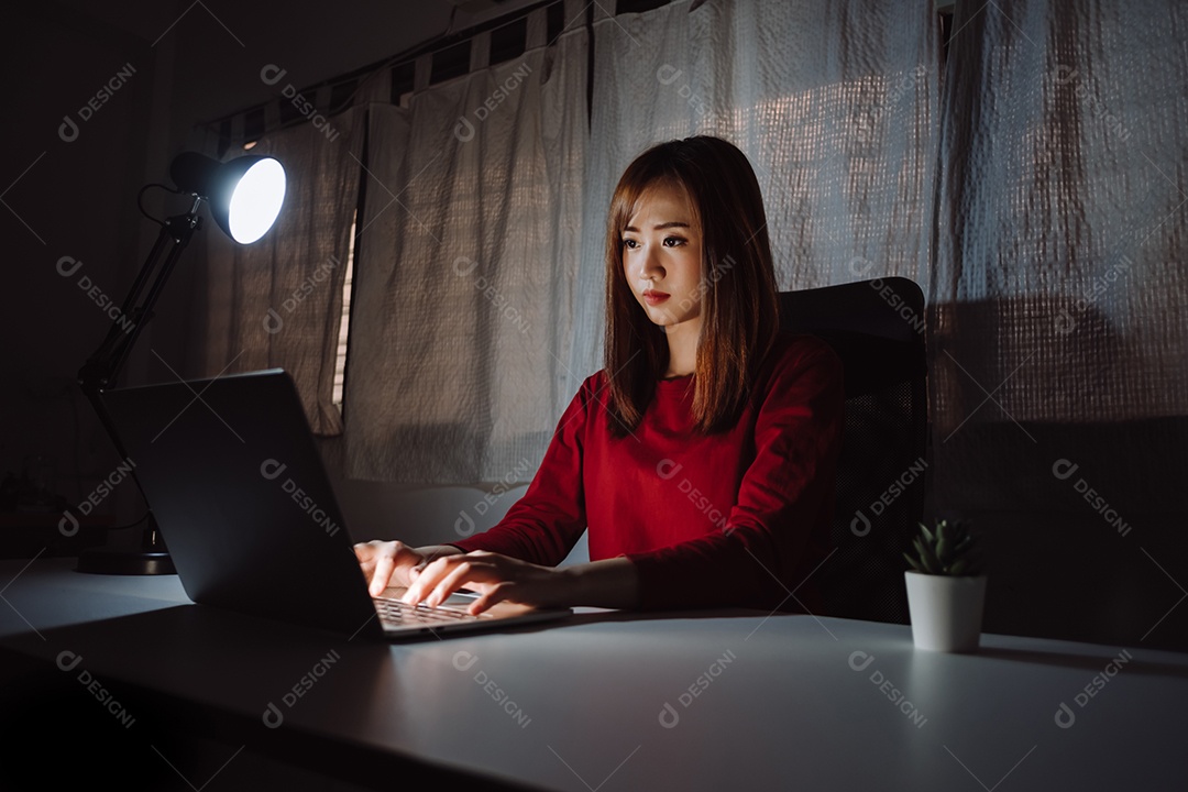 Mulher asiática trabalhando tarde da noite com laptop em casa