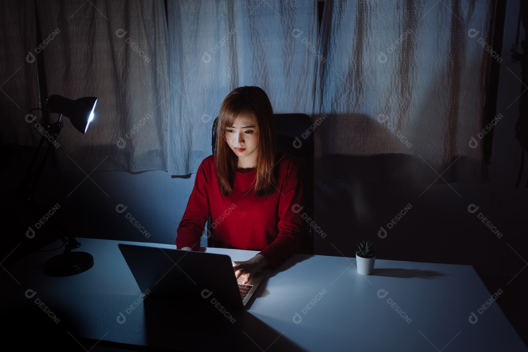Mulher asiática trabalhando tarde da noite com laptop em casa