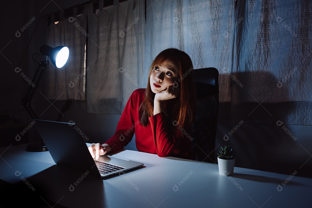 Mulher asiática trabalhando tarde da noite com laptop em casa