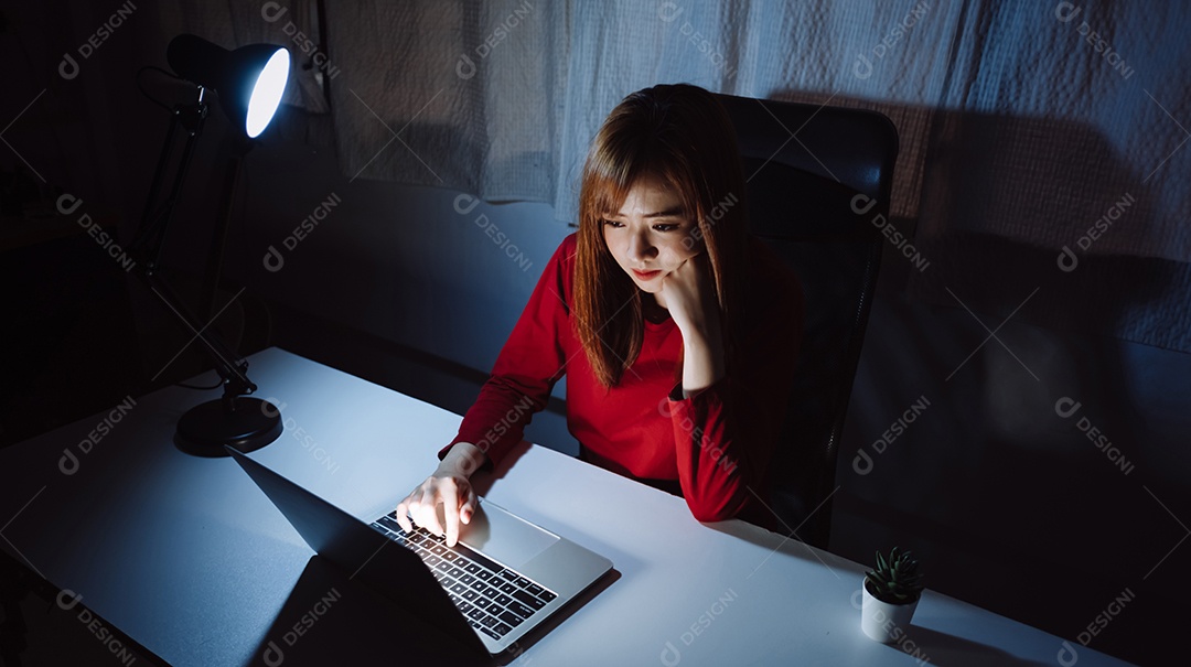 Mulher asiática trabalhando tarde da noite com laptop em casa