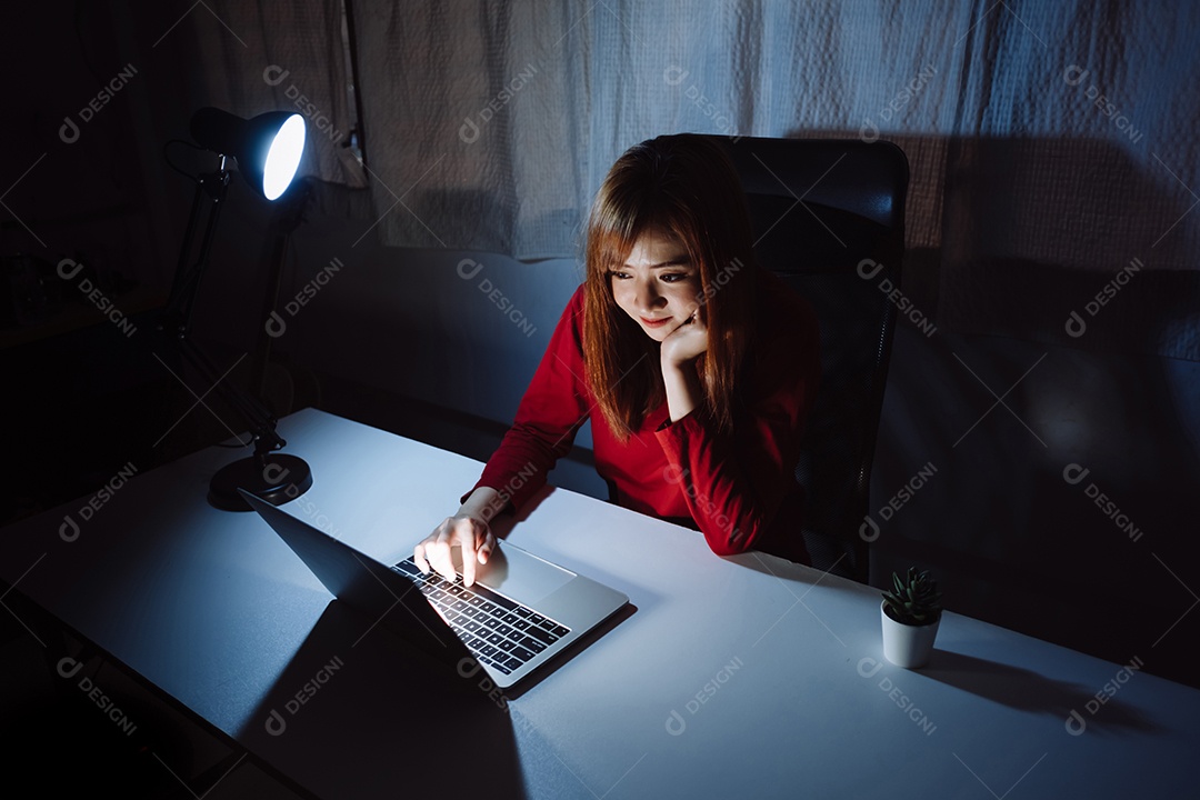 Mulher asiática trabalhando tarde da noite com laptop em casa