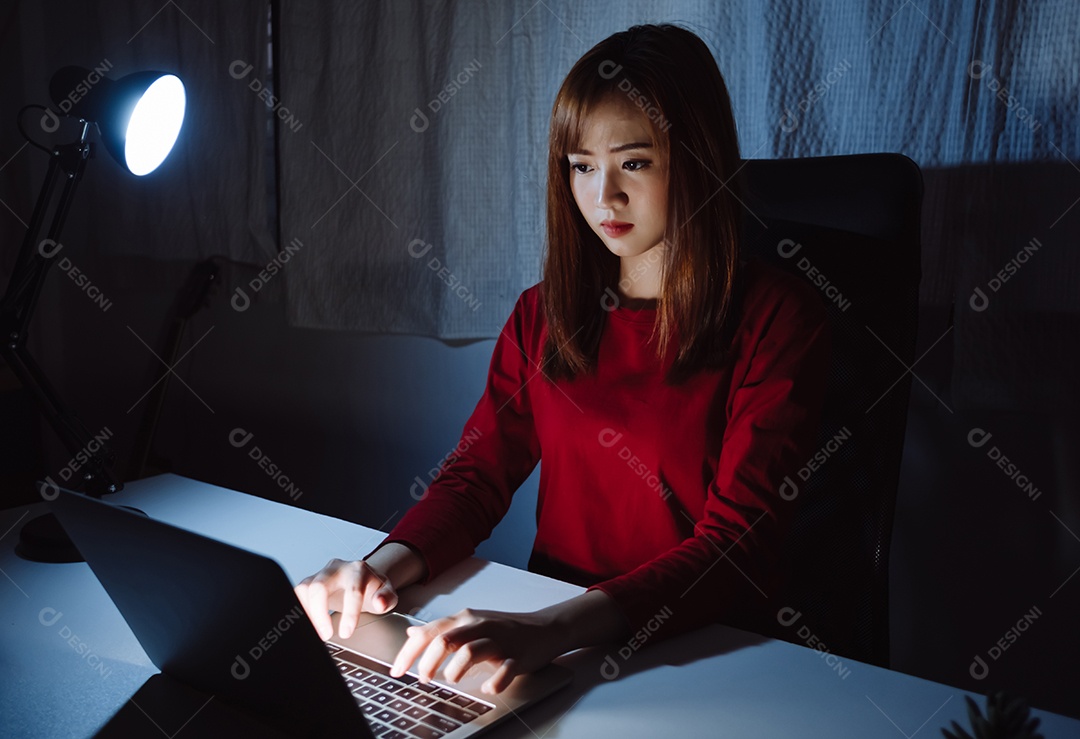 Mulher asiática trabalhando tarde da noite com laptop em casa