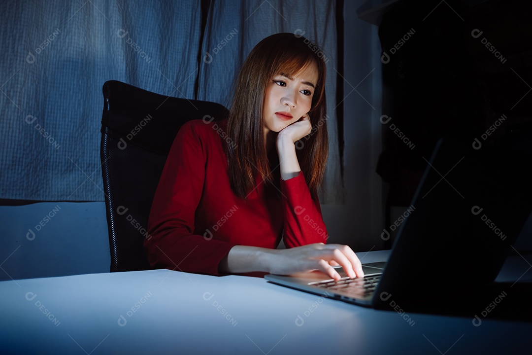 Mulher asiática trabalhando tarde da noite com laptop em casa