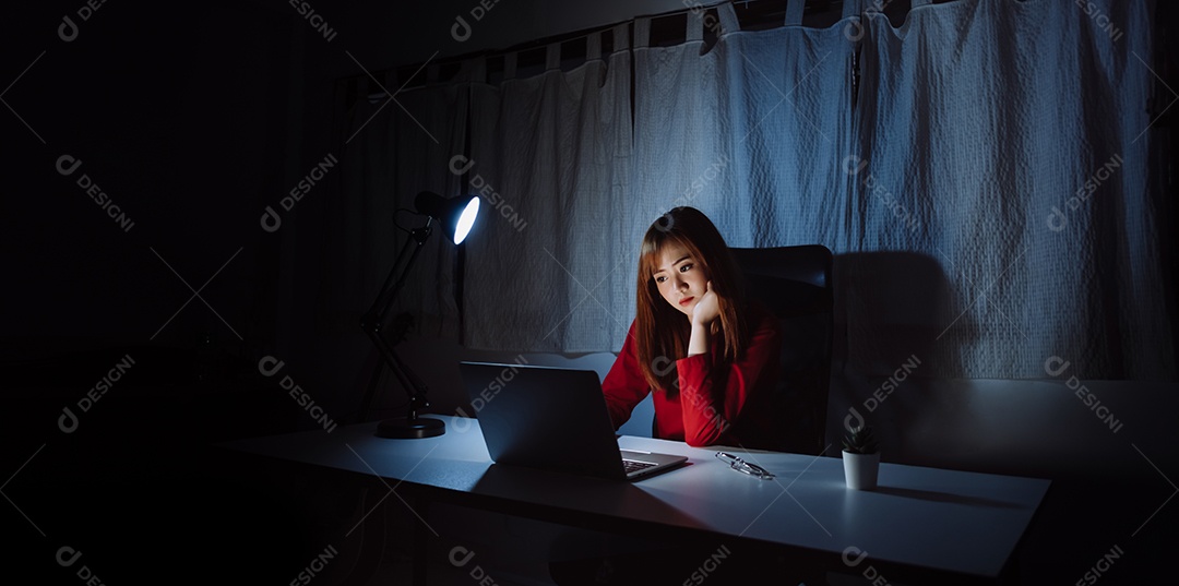 Mulher asiática trabalhando tarde da noite com laptop em casa